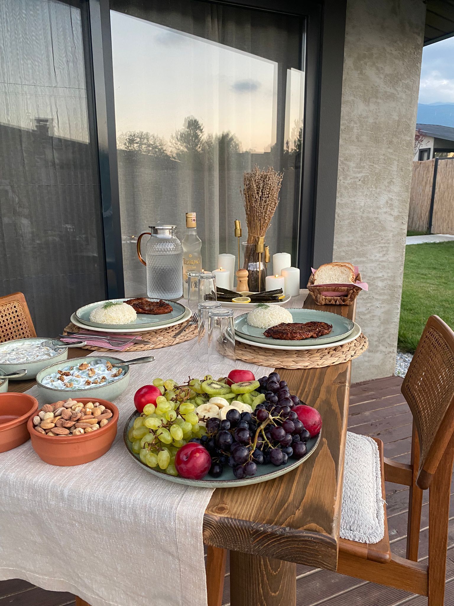 A table set for a meal with plates of food, a bowl of fruit, and candles.