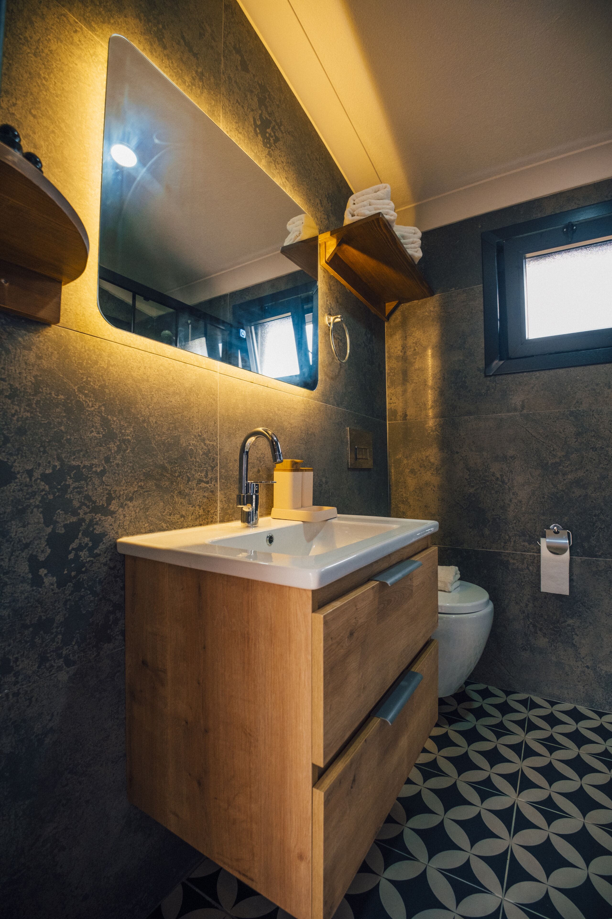 Et moderne badeværelse med en trævæg, et stort spejl og et toilet.
