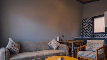 Una habitación acogedora con un sofá gris, una mesa de centro de madera y una pared con estampado.