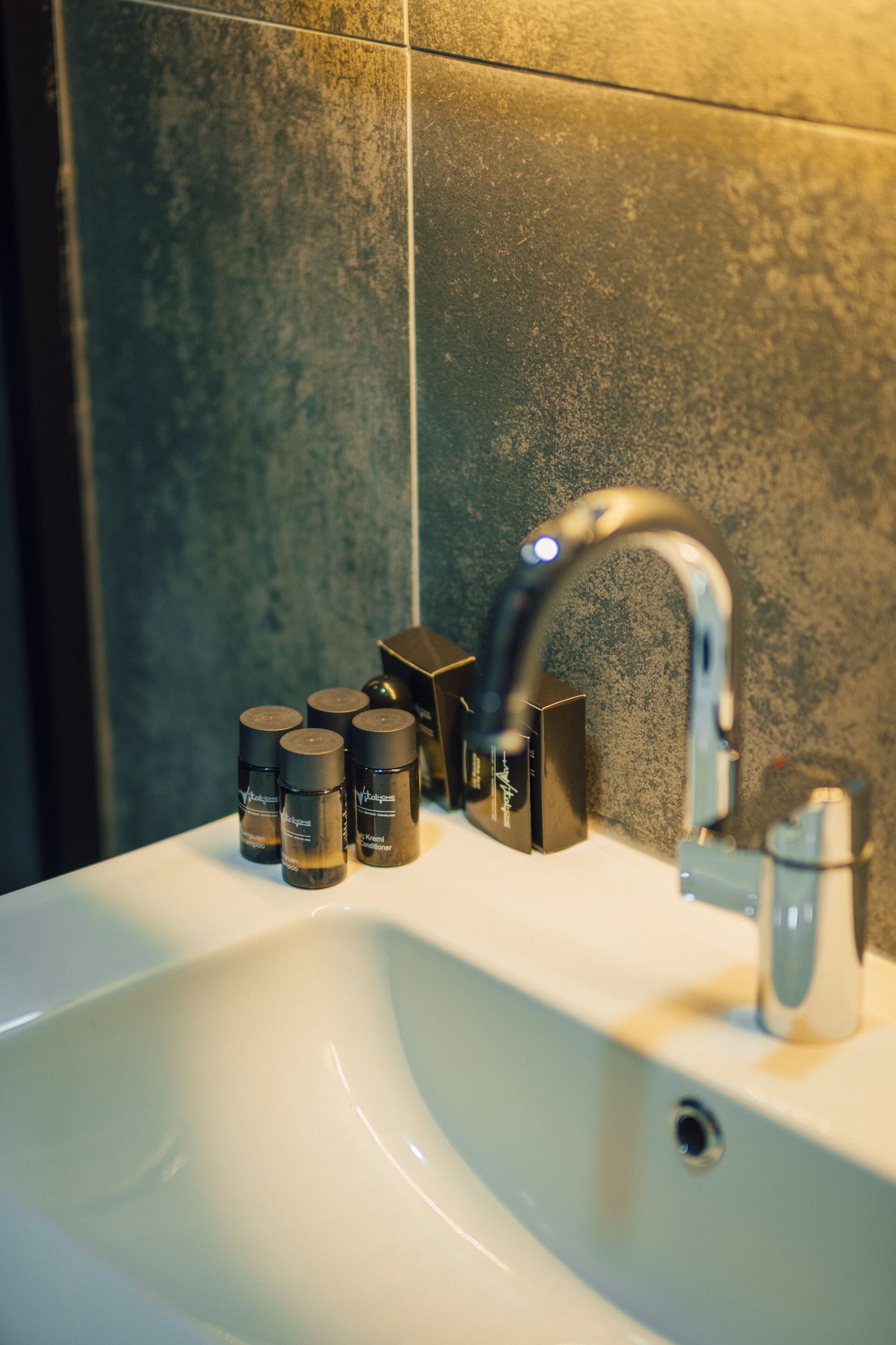 A bathroom sink with a modern faucet, a mirror, and several toiletries.