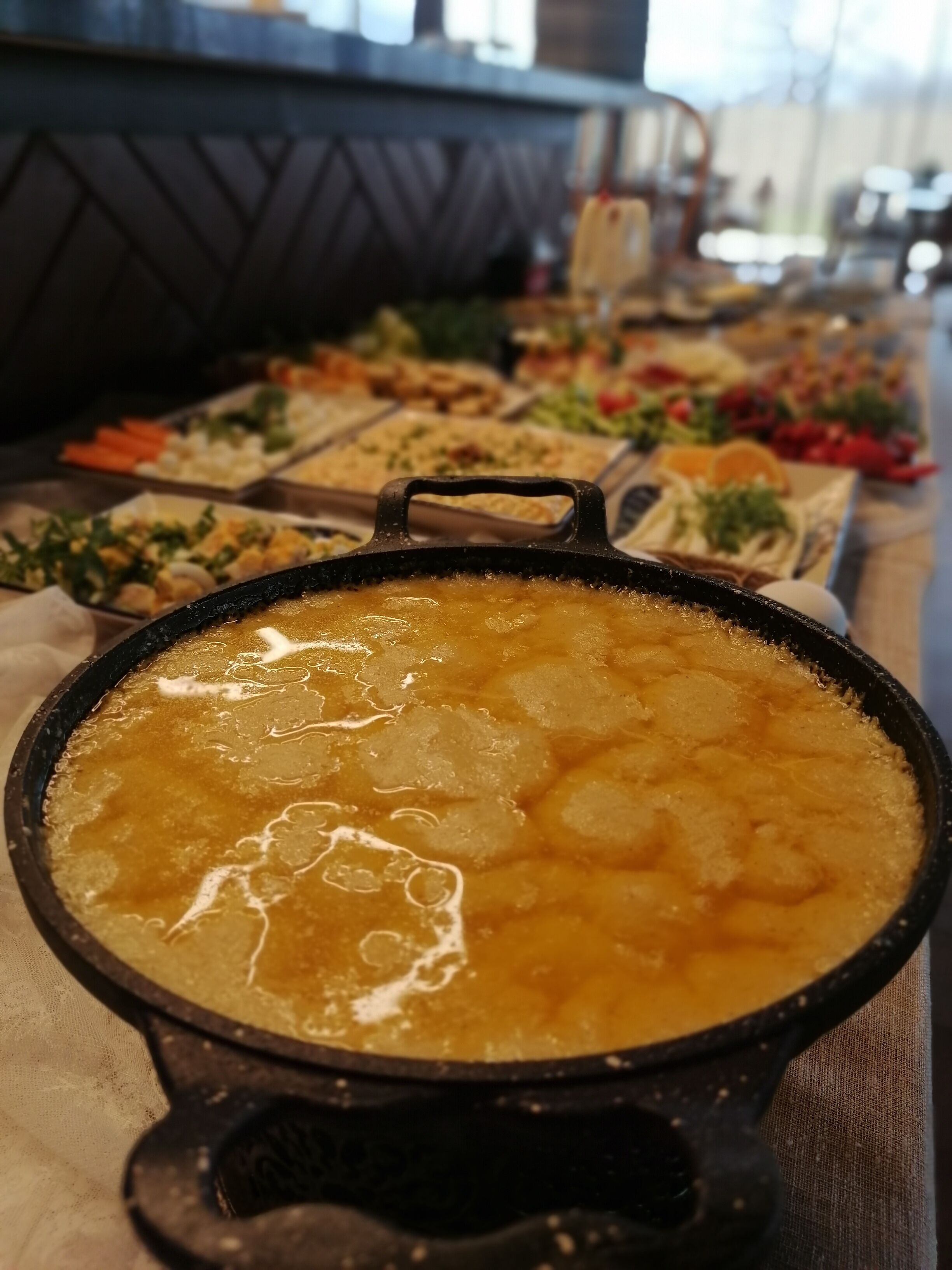 A buffet with various dishes, including a pot of soup in the foreground.