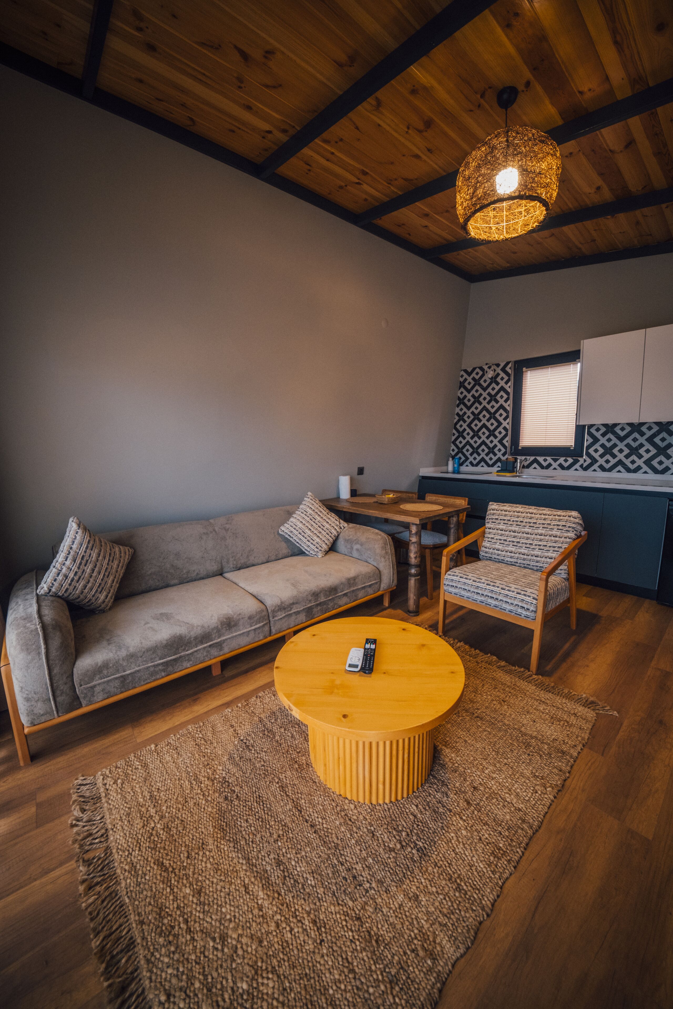 Una sala acogedora con un sofá, sillones, una mesita de centro y una lámpara colgante.