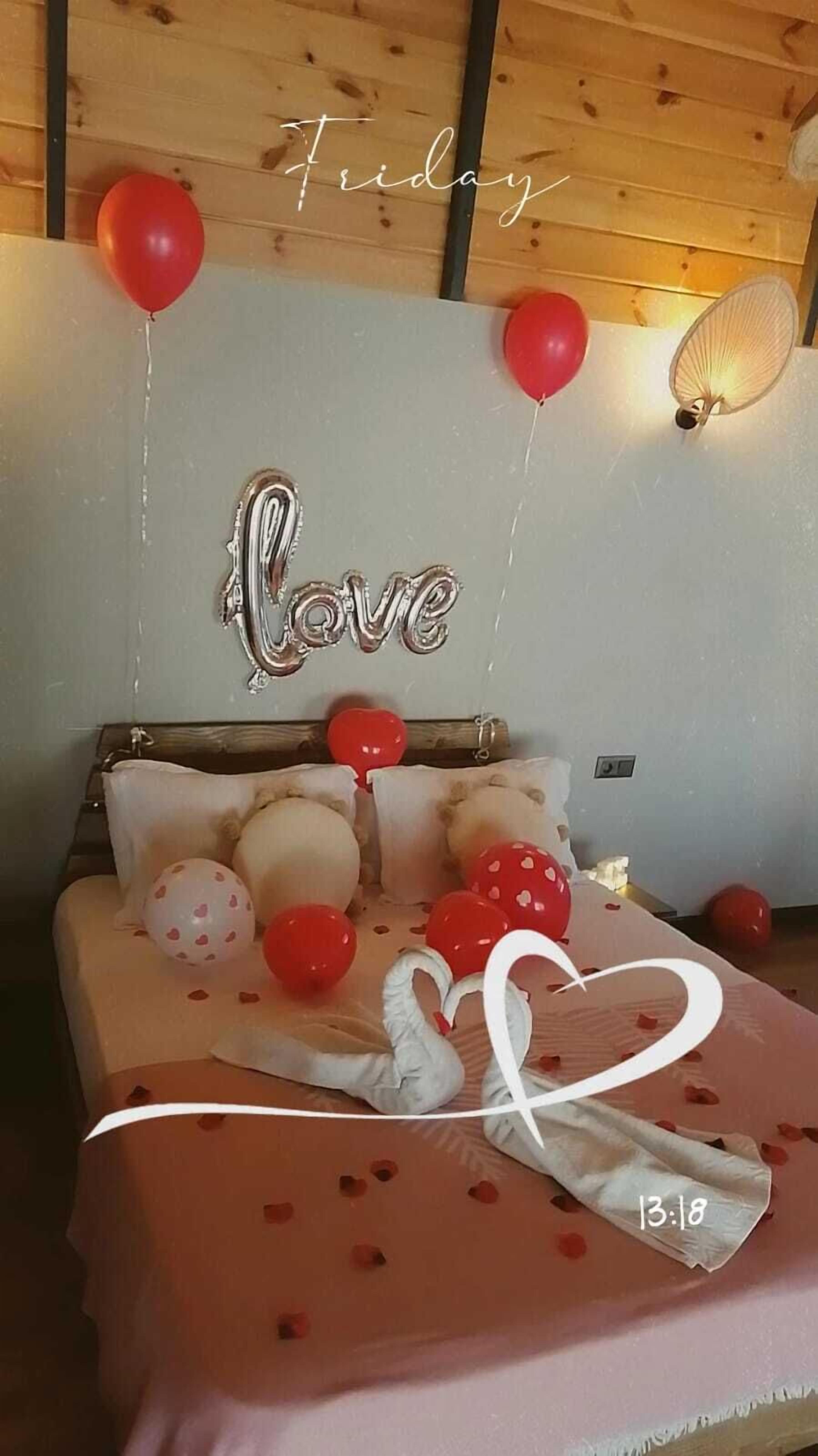 Un dormitorio con una cama, globos y un cartel que dice 'Love'.