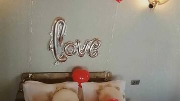 Un dormitorio con una cama, globos y un cartel que dice 'Love'.