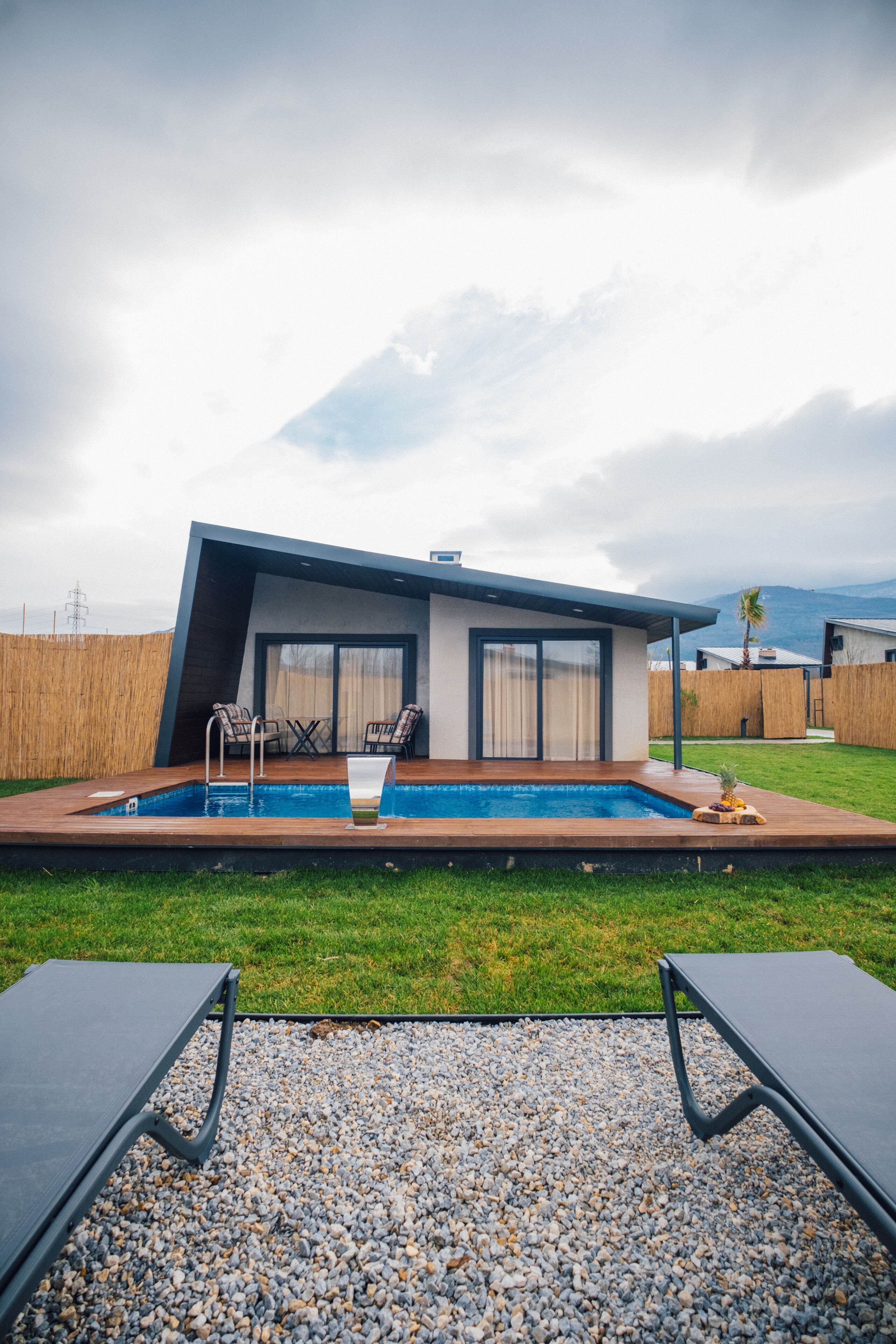 Une maison moderne dotée d’une piscine, d’un espace salon extérieur et offrant une vue sur les montagnes.
