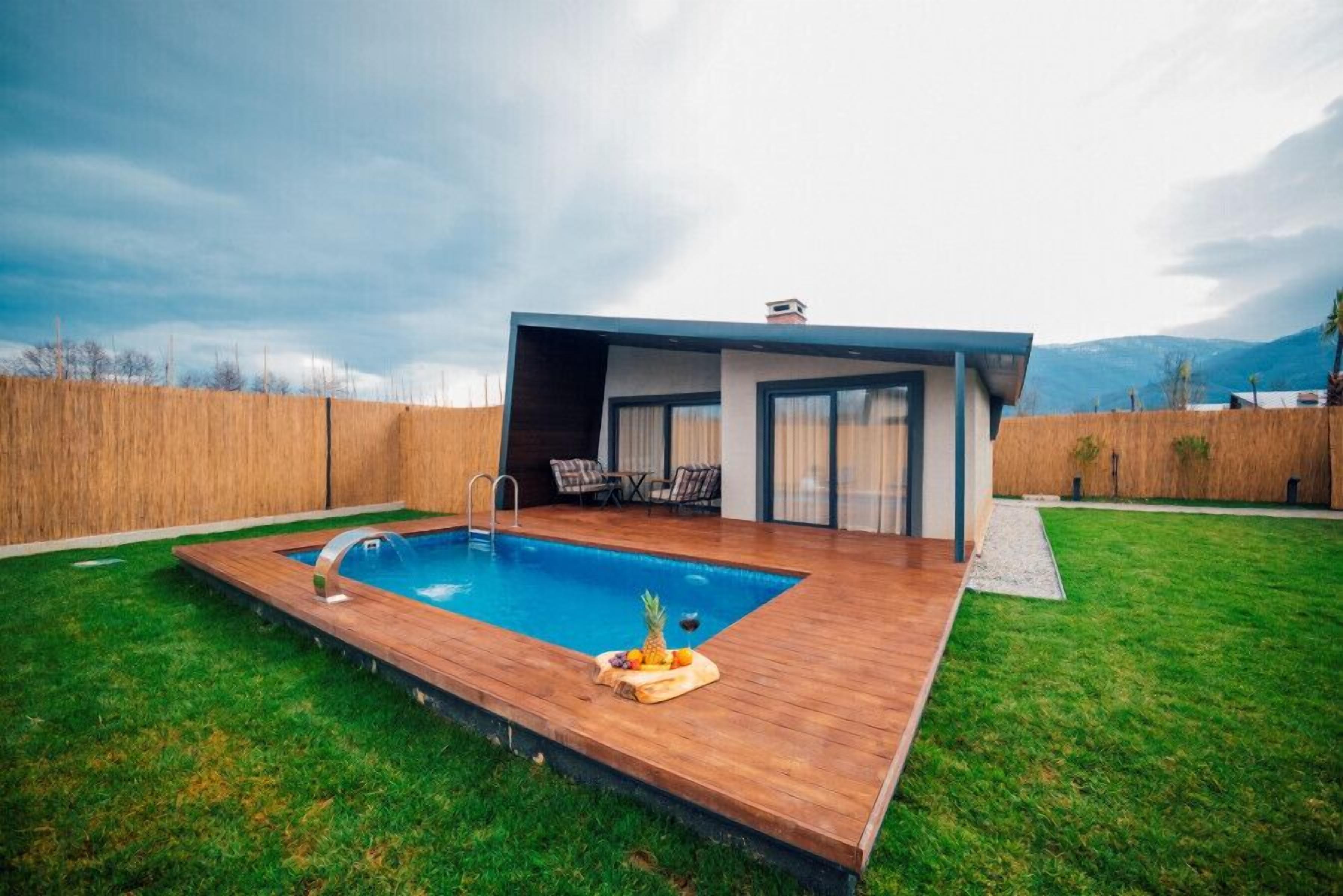 Una casa moderna con piscina, un patio con mobiliario exterior y vistas a la montaña.