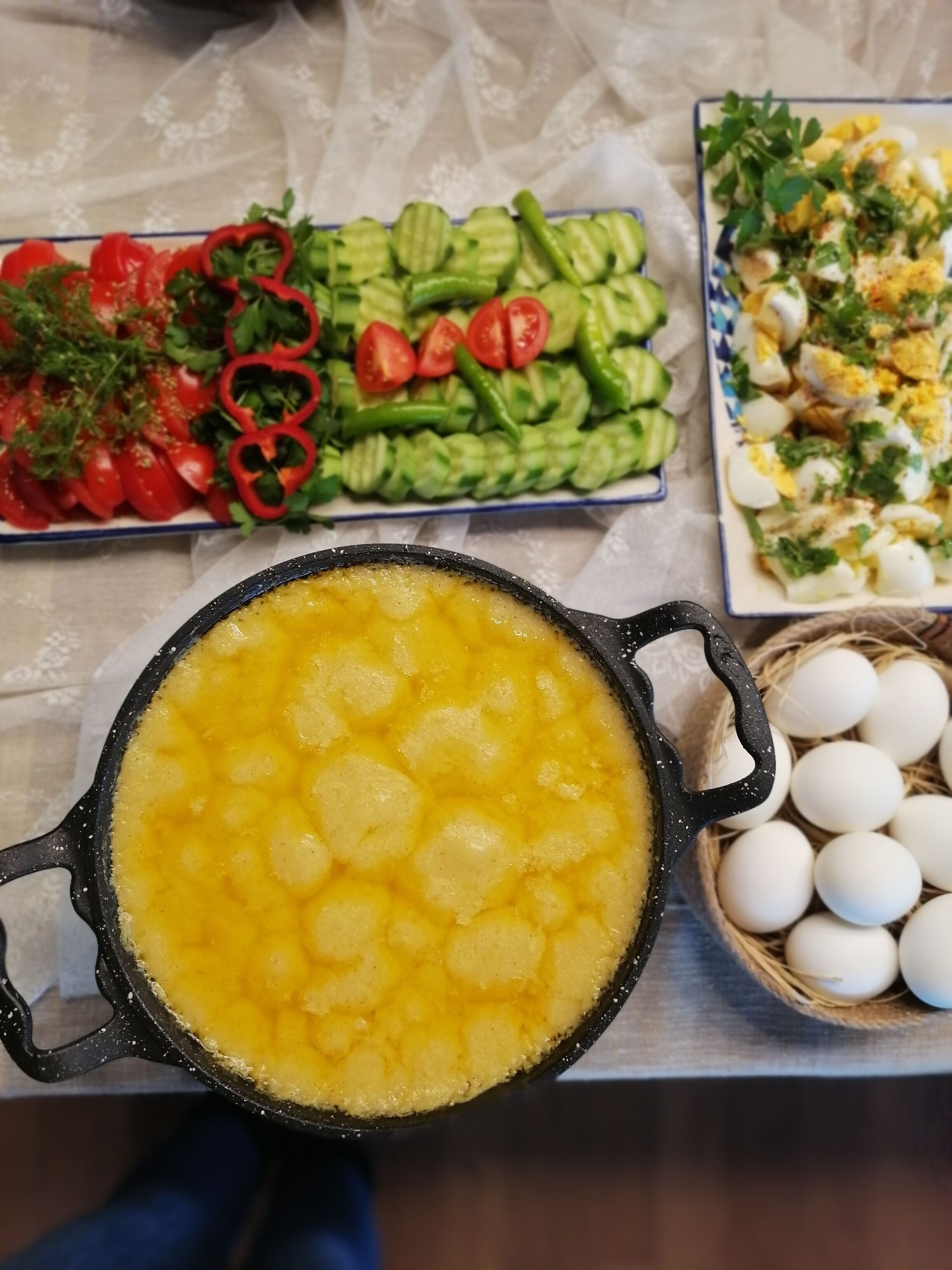 A pot of yellow food, possibly a dessert, on a table with various dishes including vegetables and eggs.