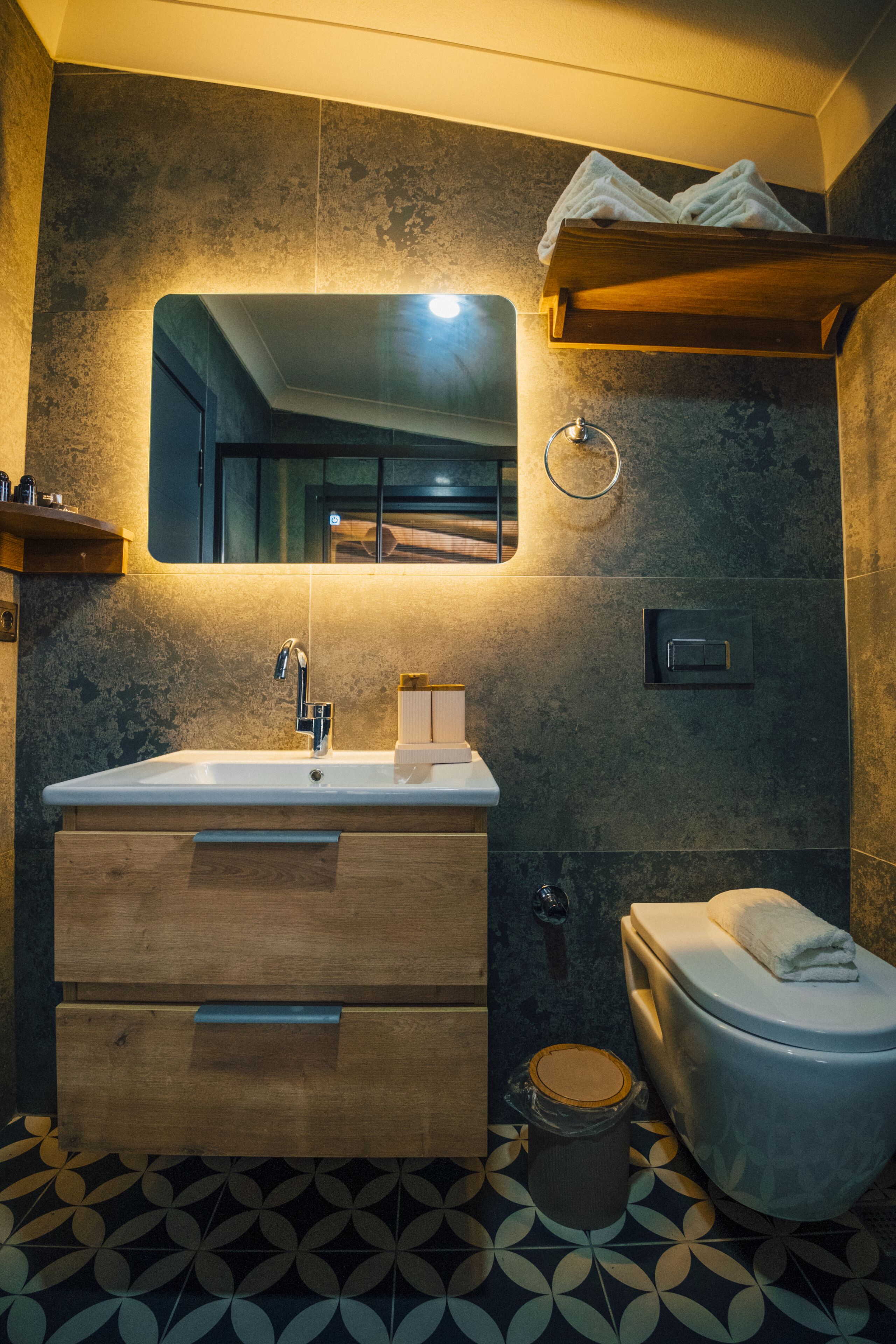 A modern bathroom with a large mirror, a sink, a toilet, and a wooden vanity.
