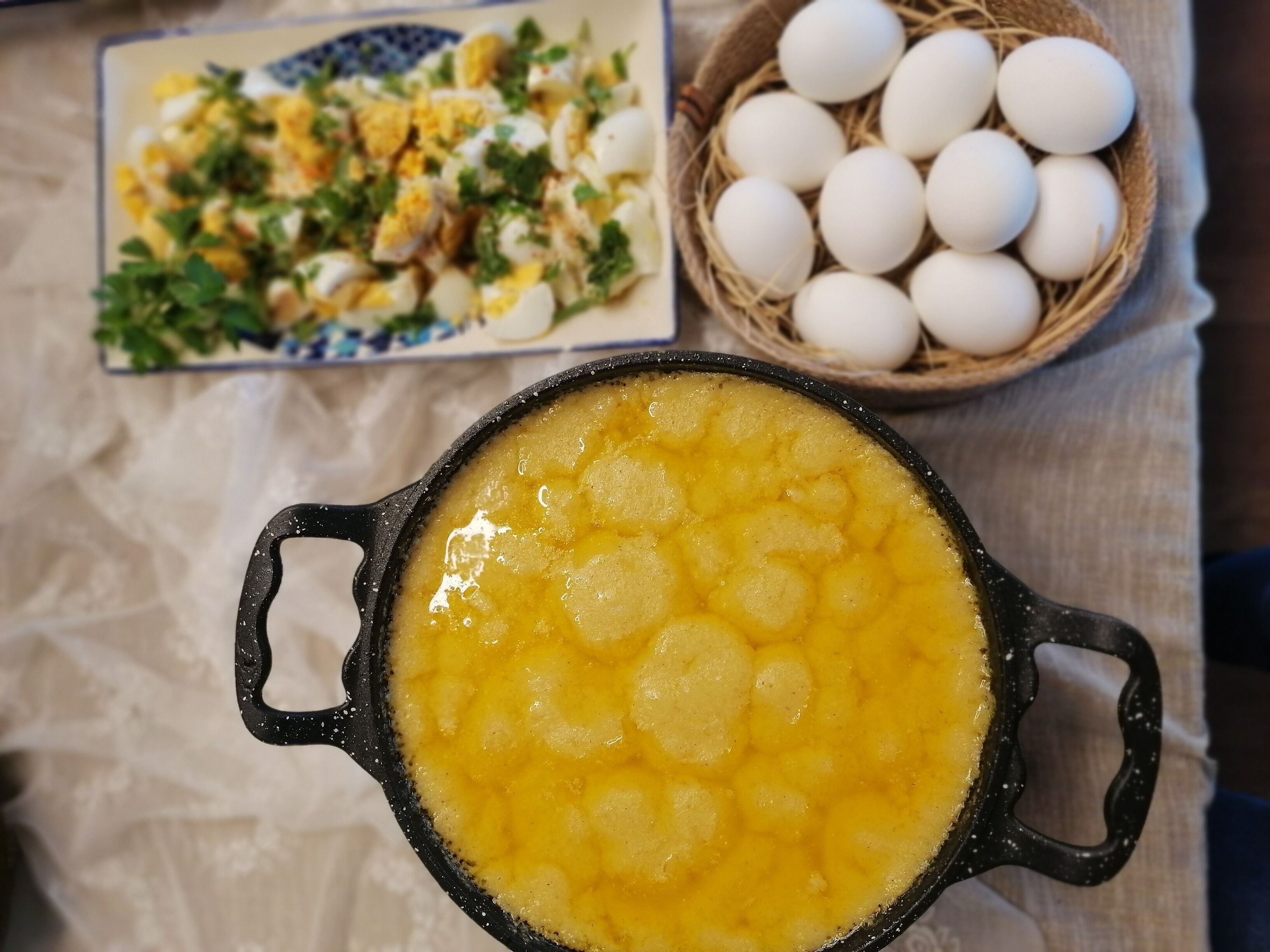 A pot of yellow food, a bowl of eggs, and a plate of food.