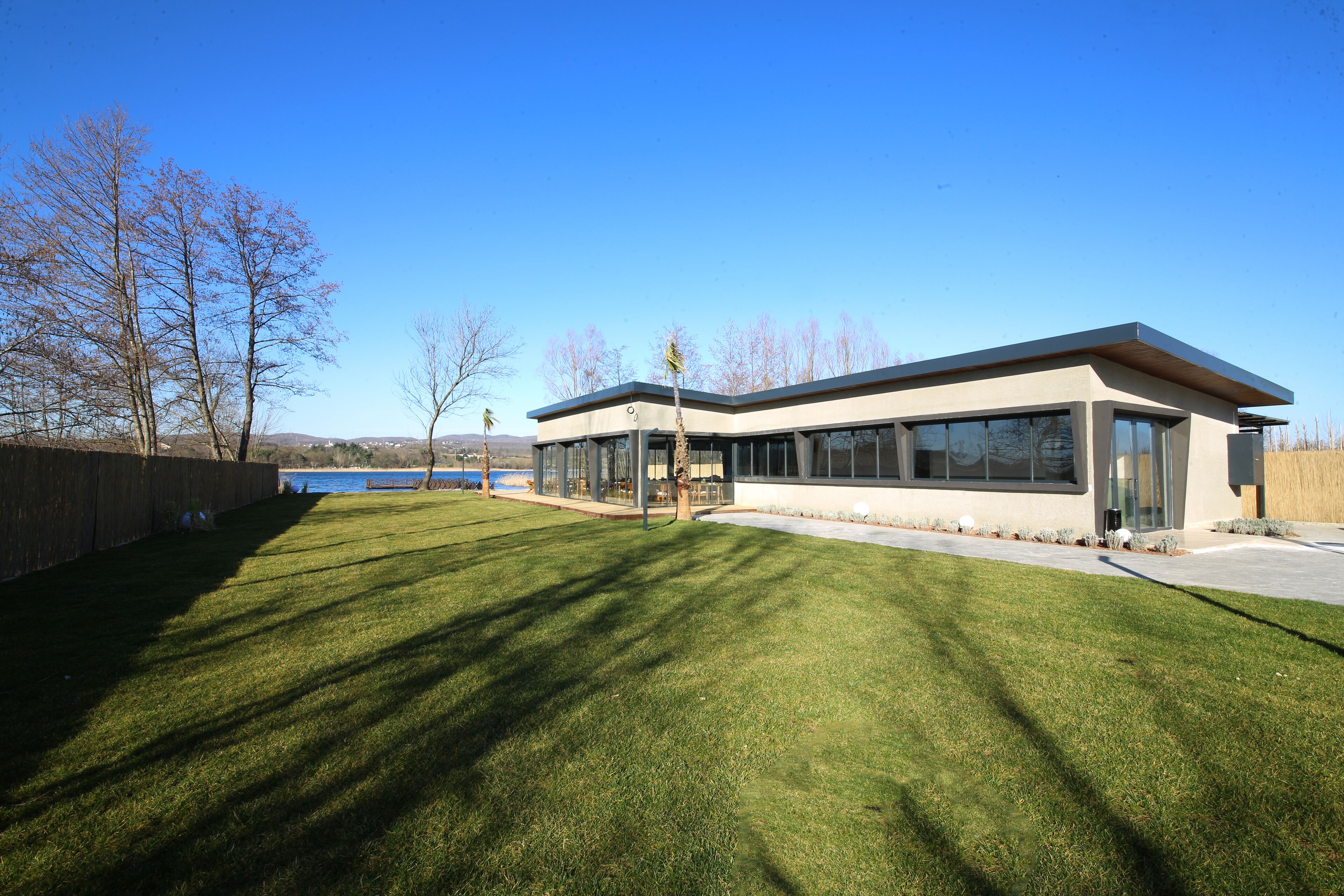 A modern building with large windows and a flat roof, surrounded by a well-maintained lawn and trees.