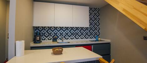 A kitchen with a white countertop, two wooden chairs, and a patterned backsplash.
