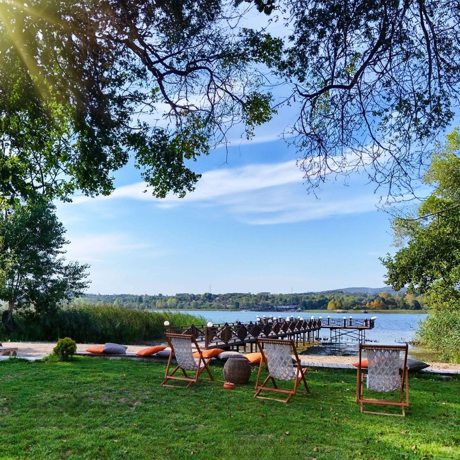 An outdoor seating area with chairs and tables, overlooking a lake with a dock and boats.