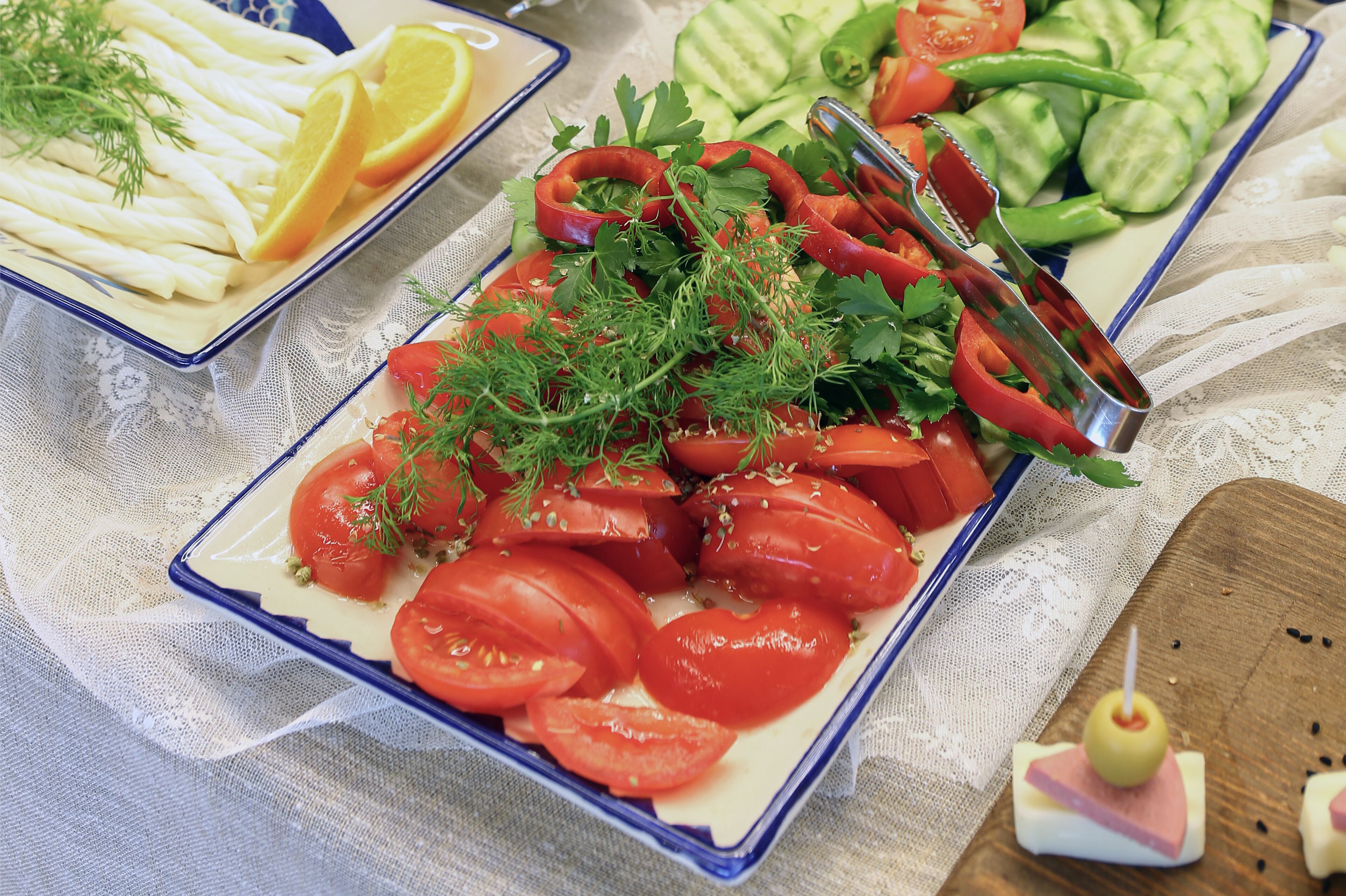 Un plat contenant des tomates en tranches, des herbes et un ustensile de cuisine en métal.