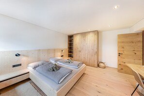 Une chambre moderne avec un lit en bois, des étagères intégrées et une armoire en bois.