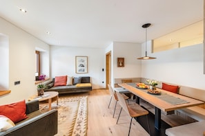 Un salon moderne comprenant un canapé, une table basse et un coin repas avec des chaises et une table en bois.