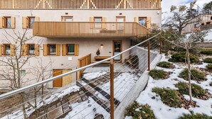 Een meerhoog gebouw met een houten balkon, een trap en een met sneeuw bedekte grond.