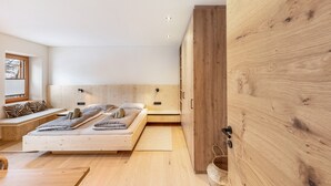 Een minimalistische slaapkamer met een houten bed, een inbouwkbank en een grote inloopkast.