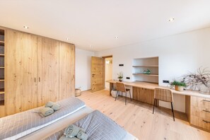 Une chambre à coucher moderne avec une armoire en bois, un bureau et un lit.