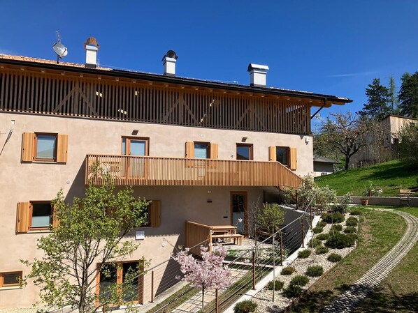 Un bâtiment à deux étages doté d’un balcon, d’un petit jardin et surplombant un ciel dégagé.