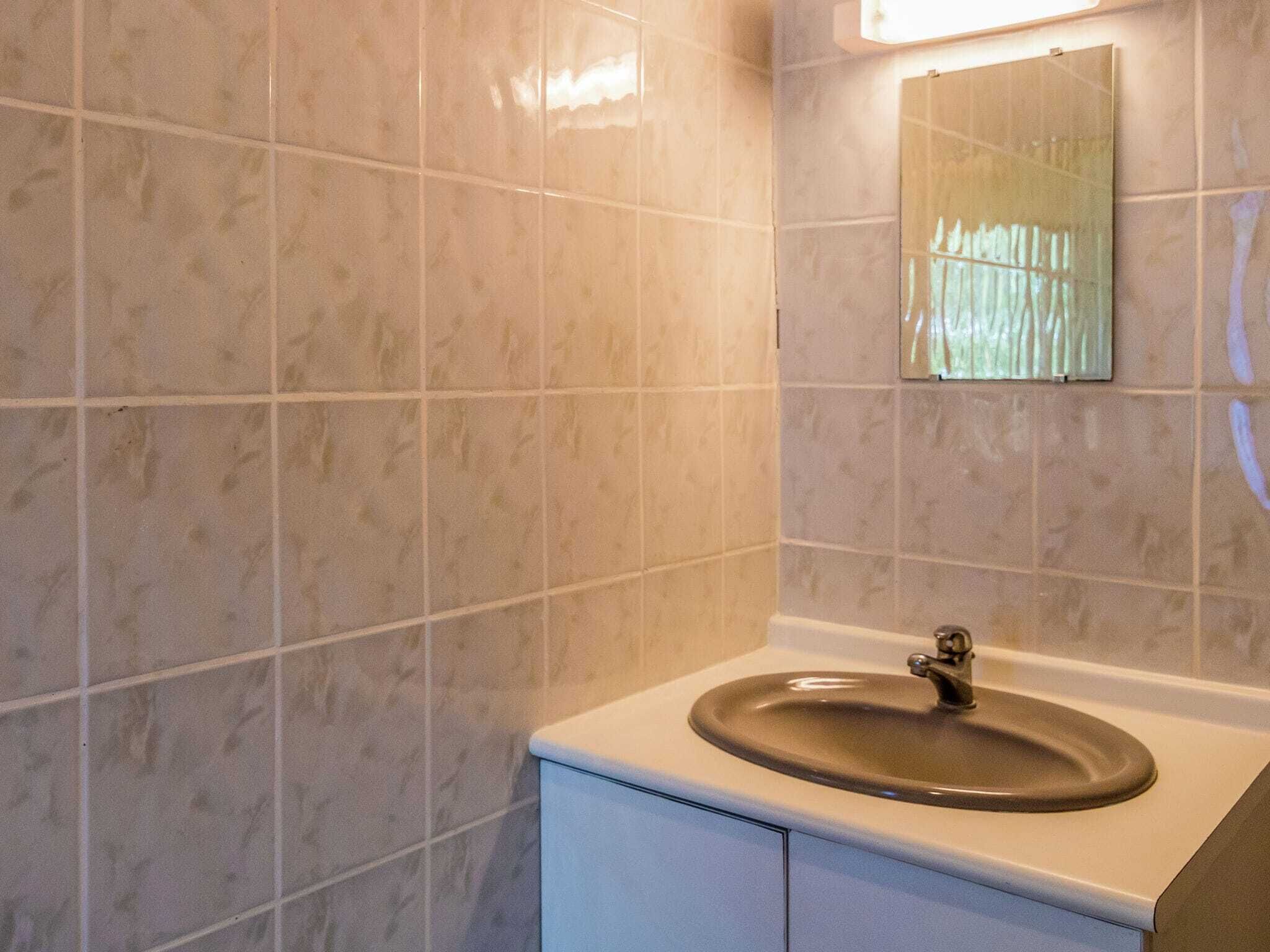 A bathroom with a sink, mirror, and tiled walls.