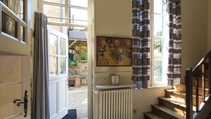 A room with a wooden staircase, a radiator, and a painting on the wall. - Castle in Chaleix with Pool and Views (Chalais)