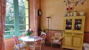 Un comedor con una mesa y sillas, un armario amarillo y una ventana con cortinas.