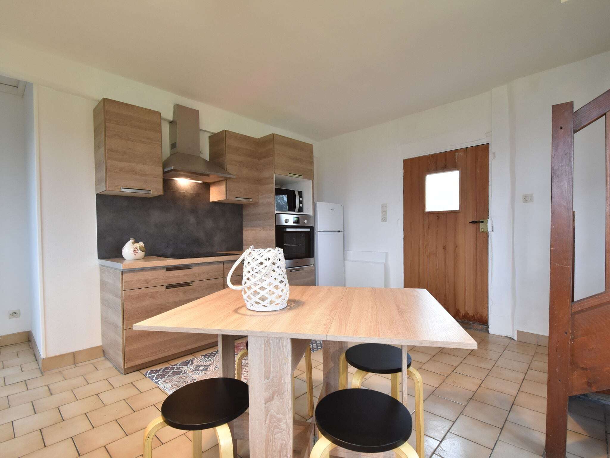Une cuisine moderne avec des meubles en bois, un four encastré et une bouilloire blanche posée sur le plan de travail.
