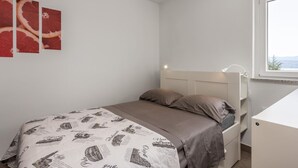 Een slaapkamer met een bed, nachtkastje, bureau en een raam met uitzicht.