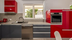 Een moderne keuken met rode kastjes, een roestvrijstalen vaatwasser en een inbouwoven.