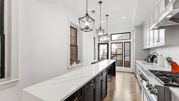 A modern kitchen with white cabinetry, a long countertop, and a gas stove. - The Lincoln | Entire 7BR DC Rowhome | Sleeps 14 (Washington)