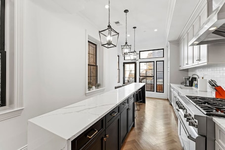 A modern kitchen with white cabinetry, a long countertop, and a gas stove.