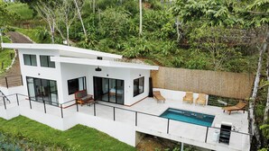 A modern house with a large balcony, a swimming pool, and lush greenery. - 1bdr Stunning House Uvita CUSINGA | Panoramic Ocean View (Bahía Ballena)