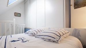 A bed with striped bedding, a white headboard, and a small picture frame on the wall.