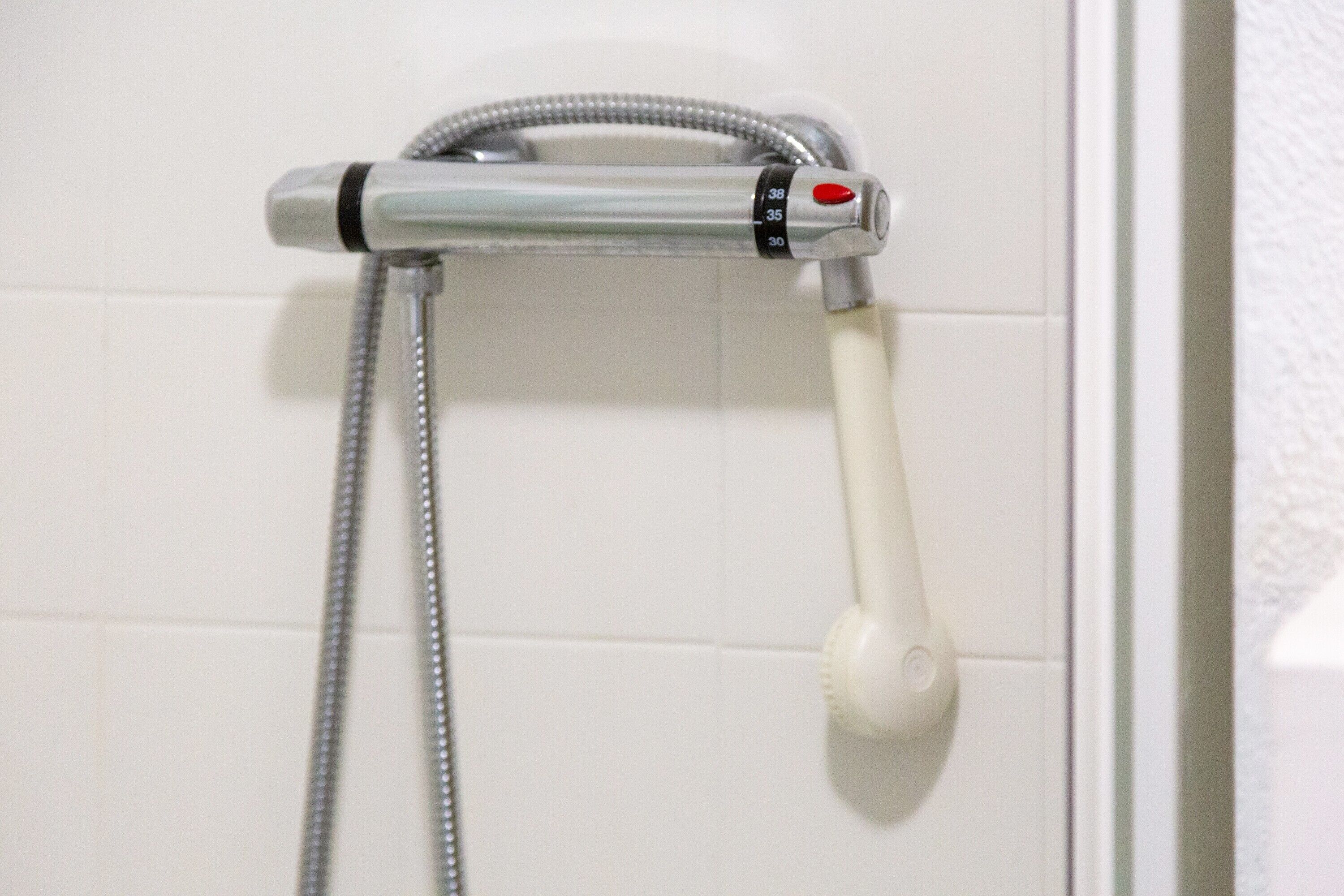 Een douche met een handdouche en flexibele slang.