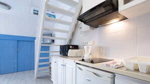 A compact kitchen with white cabinets, a toaster, a coffee maker, and a white sink. - Apartment 'Guillaume' with Sea View (tregunc)