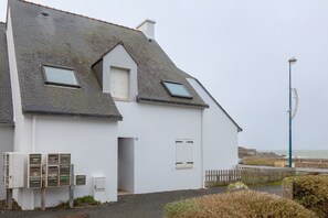 En hvid bygning med skråtag, et lille vindue og en el-tavle.