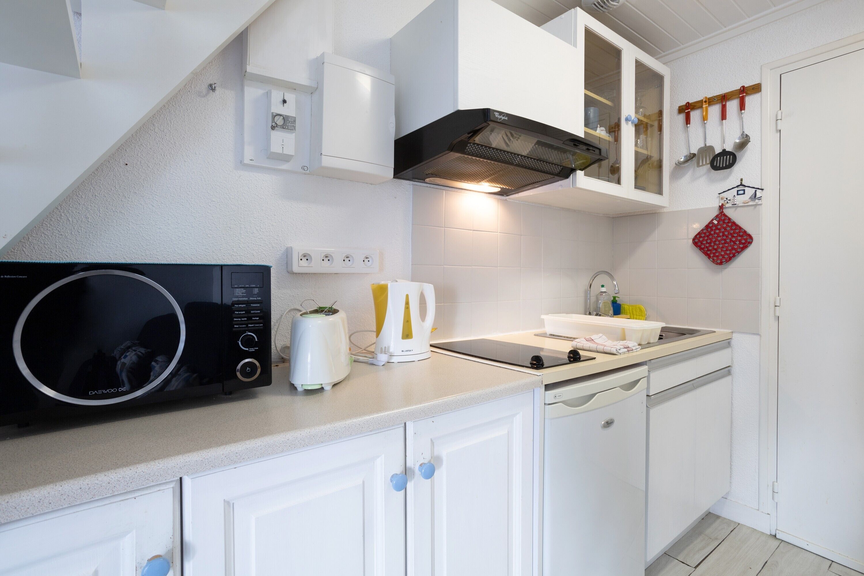 Una cocina equipada con microondas, tostadora, hervidor, pileta y muebles bajos.