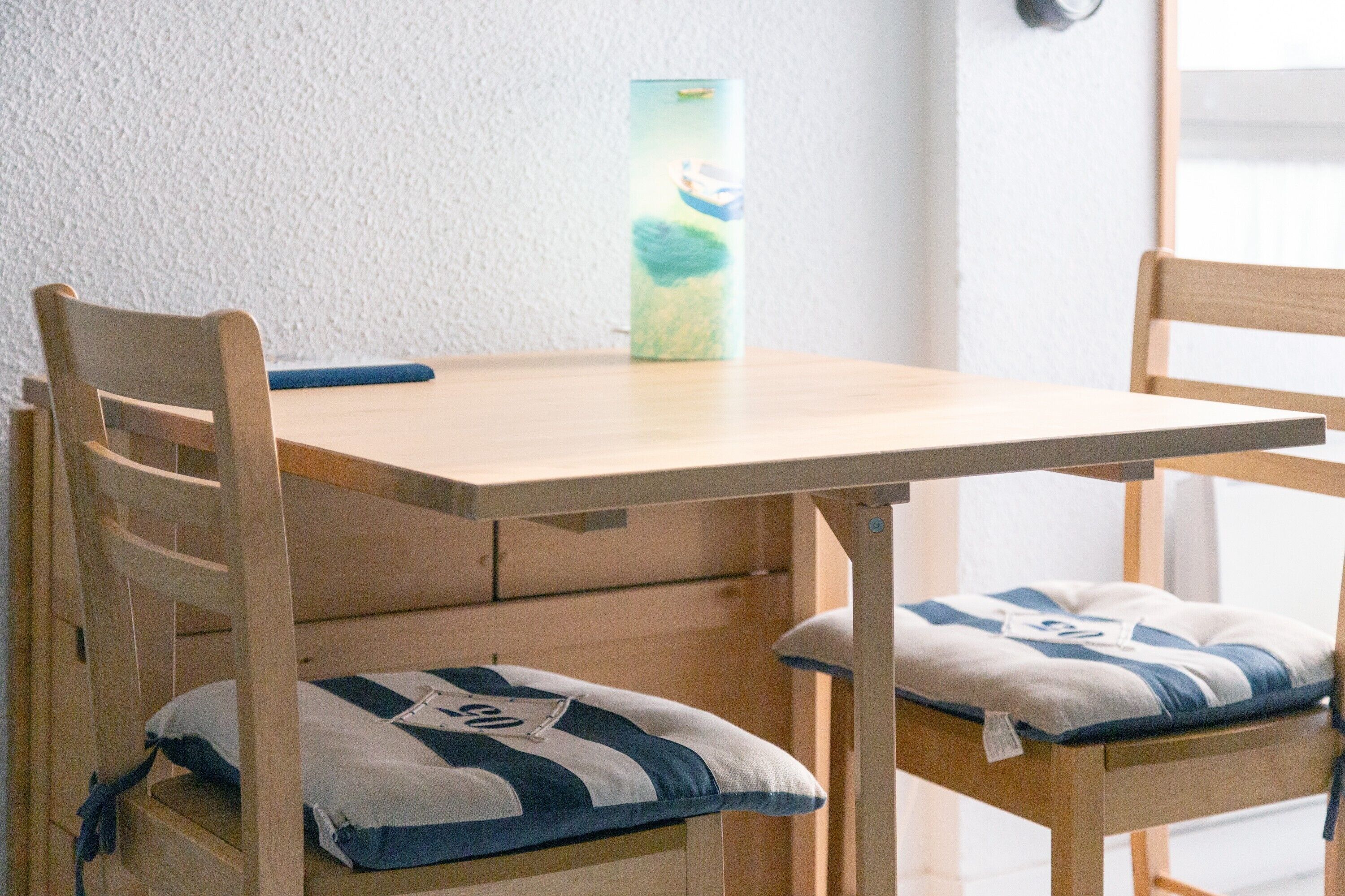 Ein Holztisch mit zwei Stühlen, jeder mit einem Streifenmuster-Kissen.