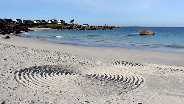 A beach with footprints, a large rock, and houses in the background. - Apartment 'Guillaume' with Sea View (tregunc)