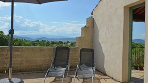 An outdoor seating area with two chairs and a table under an umbrella, overlooking a scenic landscape with mountains and greenery. - Villa in Saint-Privat-de-Champclos with pool (Barjac)