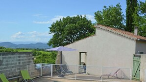 A swimming pool with a view of mountains, a small building with a tiled roof, and a green umbrella. - Villa in Saint-Privat-de-Champclos with pool (Barjac)