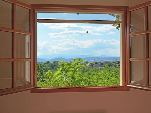 A room with a large window offering a view of a lush green landscape and distant mountains.