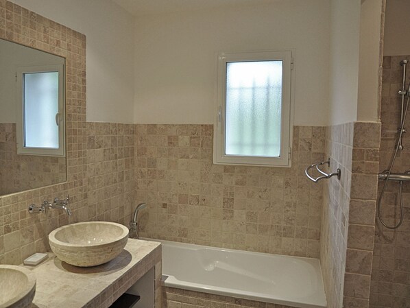 Une salle de bain avec une baignoire, deux lavabos, une fenêtre et une douche.