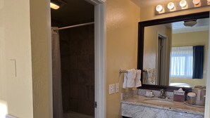 Une salle de bain avec une douche, un lavabo avec un miroir et un porte-serviettes.