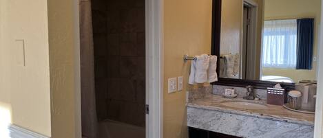 A bathroom with a shower, a sink with a mirror, and a towel rack.
