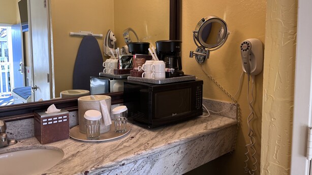 Une salle de bain d’hôtel avec un lavabo en marbre, une machine à café, un sèche-cheveux et un miroir.