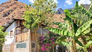 A rustic building with a corrugated metal roof, a small window, and a wooden door. - The Hub (San Juan La Laguna)