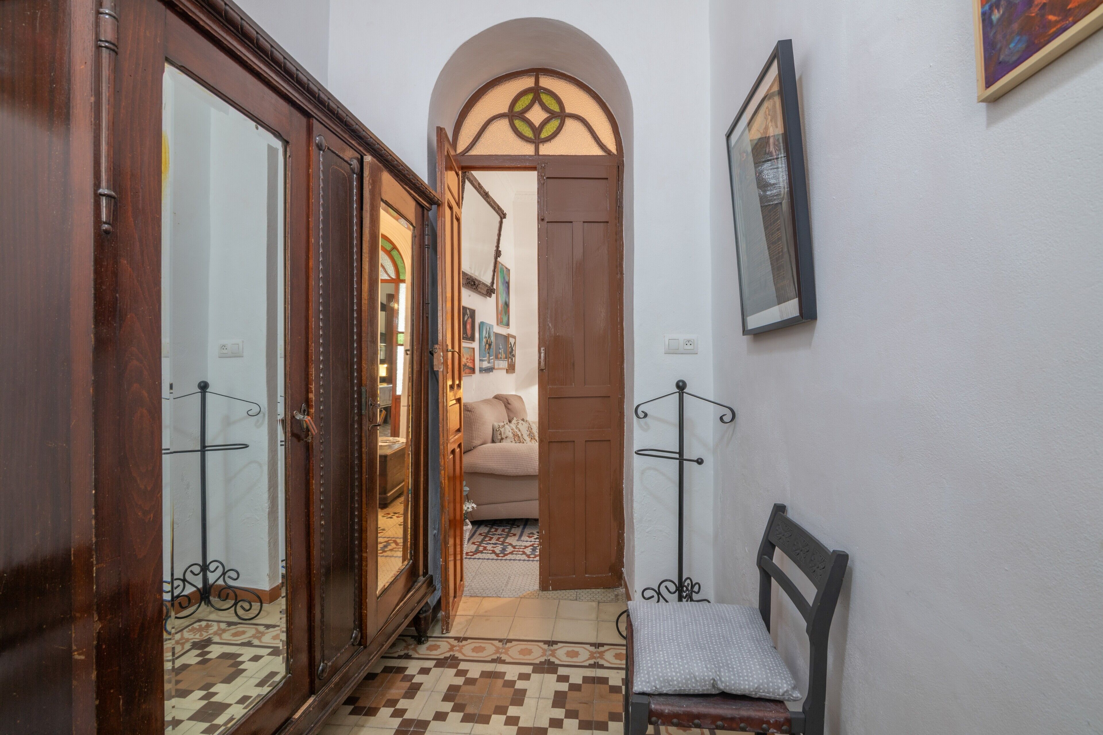 A hallway with a wooden door, a bench, and a tiled floor.