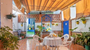Une terrasse avec une table et des chaises, des plantes en pot et une porte bleue.