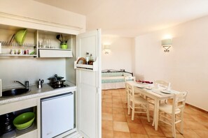A compact kitchen with a sink, stove, and storage shelves. Adjacent is a dining area with a table and chairs.